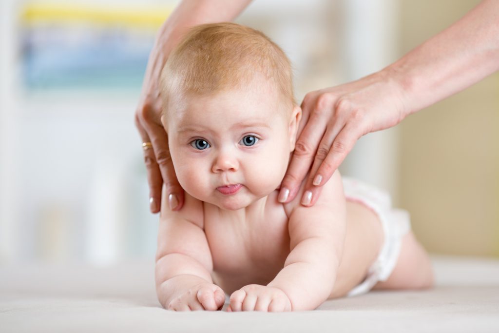 Mother making massage to her baby at home. Health care and medicine concept.